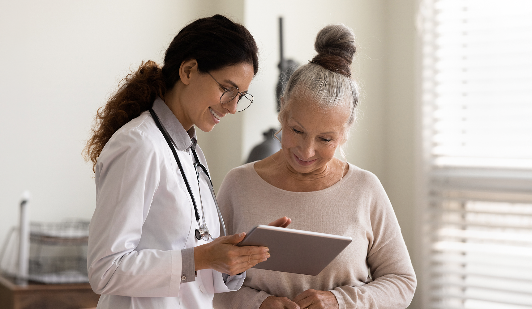 Médica atendendo paciente idosa com um tablet