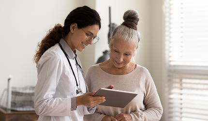Médica atendendo paciente idosa com um tablet